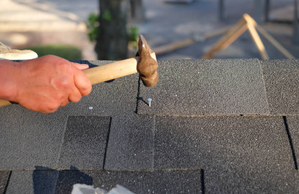 istock Contractor installing corner bitumen roof shingles with hammer and nails. 962984004