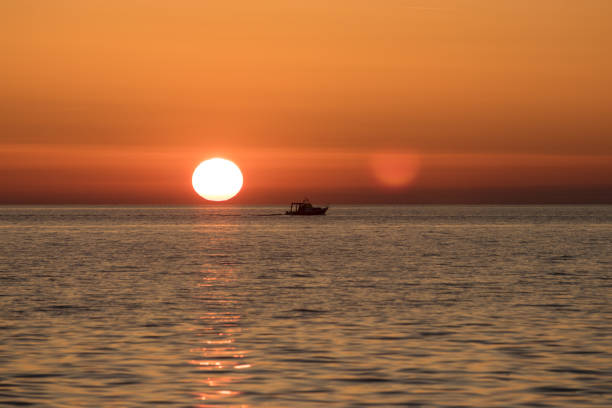Boat sailing over the sea with sun setting in the back