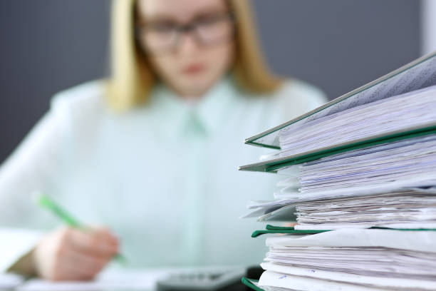 istock Bookkeeper or financial inspector  making report, calculating or checking balance. Binders with papers closeup. Audit and tax service concept. Green colored image backgroun 962985310