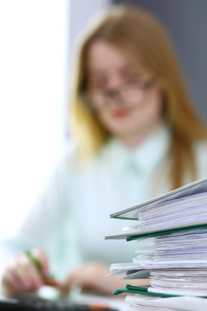 istock Bookkeeper or financial inspector  making report, calculating or checking balance. Binders with papers closeup. Audit and tax service concept. Green colored image backgroun 962985414