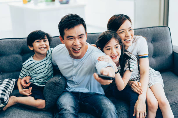 familia asiática alegre viendo la televisión juntos - malaysian person family asian ethnicity mother fotografías e imágenes de stock