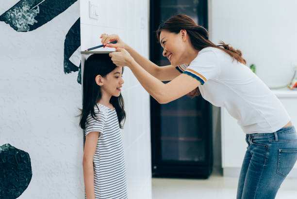 istock Mother measuring her daughter's height 962998862