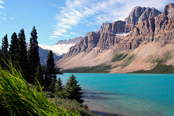 With Canadian Rocky Mountain reflections in the water, a woman an man married couple enjoy Bow Lake reflections with the Bow Glacier in the background, Banff National Park, Alberta, Canada.