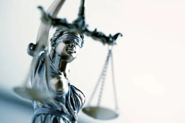 A close up and a low angle view of a statue of lady justice.  The image is photographed with a very shallow depth of field with the focus being on her face.