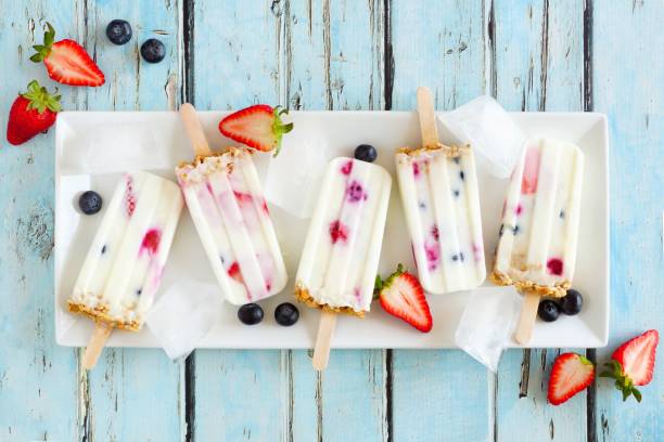 istock Mixed berry yogurt popsicles on a white plate over blue wood 963011858