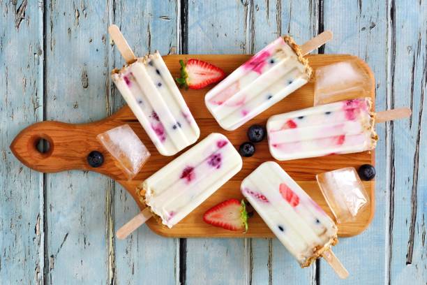 istock Mixed berry yogurt popsicles on a paddle board over blue wood 963011890