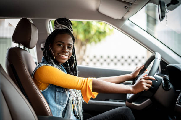 portrait of african woman sitting in car - car test drive car rental women imagens e fotografias de stock