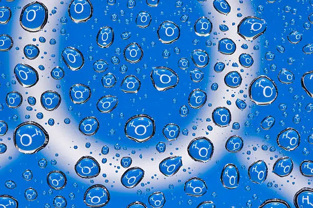 Real Water droplets on glass multiplying the white text of chemical formula of water (H2O) on blue background about a thousand times. Large droplets.