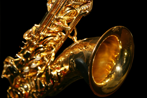 Saxophone close up. rich golden colour on a black background. focus on bell end.