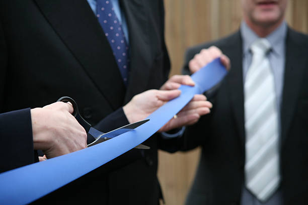 istock Businessmen in suits holding scissors cutting a blue ribbon 96307482