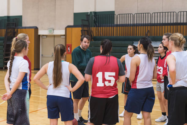 istock Coach pulls his college women's basketball team together for a huddle 963077316