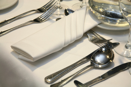 Heart plate with silverware of fork and knife with a red heart and rose petal over a pink background. Romantic dinner Valentine's Day concept