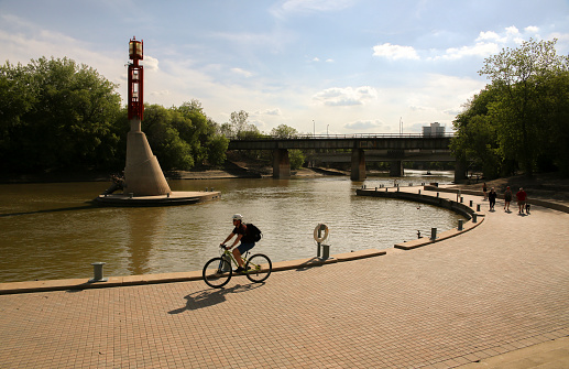 A young man riding a bike along the river in a sunny day