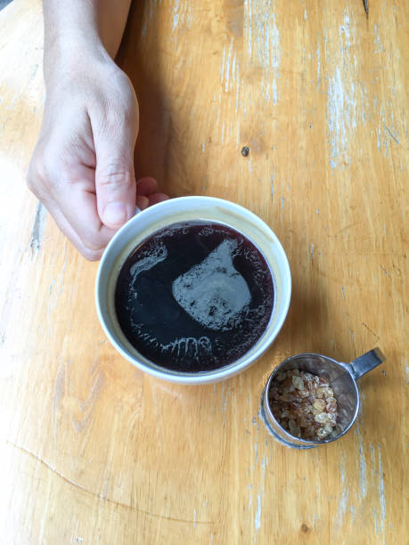 Woman's hand holding cup of black coffee on wooden background, Close up shot