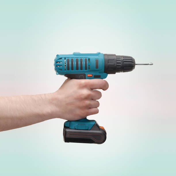 Electric screwdriver in hand at mint background Electric screwdriver in hand at mint background. holding drill stock pictures, royalty-free photos & images