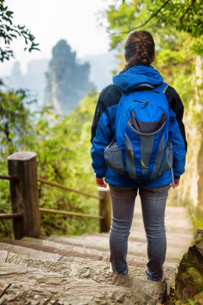 istock Young female tourist with blue backpack standing on stone stairs 963092286