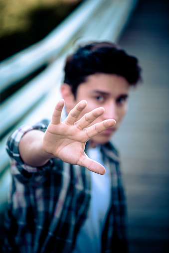 Young male teenager holding up hand in defense violence or rebellion