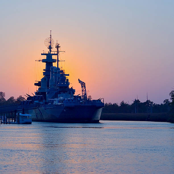 sonnenuntergang hinter dem uss north carolina - navy stock-fotos und bilder