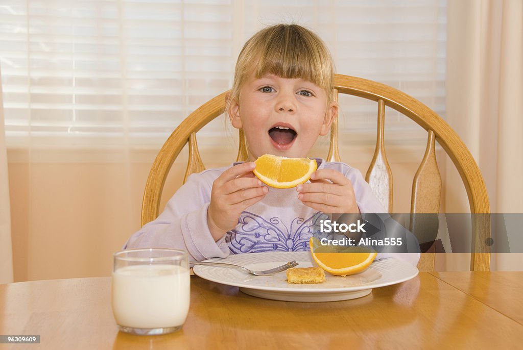 朝食のシーン-かわいい小さな女の子食べるオレンジ - 1人のロイヤリティフリーストックフォト