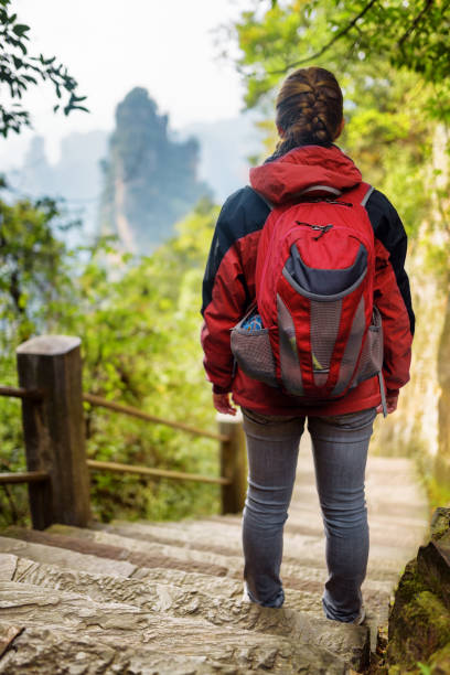 istock Young female tourist with red backpack standing on stone stairs 963096196