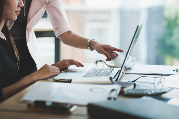 Giovani lavoratrici asiatiche che lavorano insieme in ufficio - foto stock