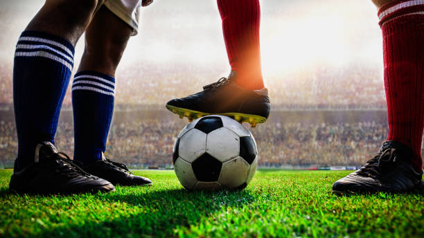 Young soccer player taking a football shot while being in mid air. There are people in the background.