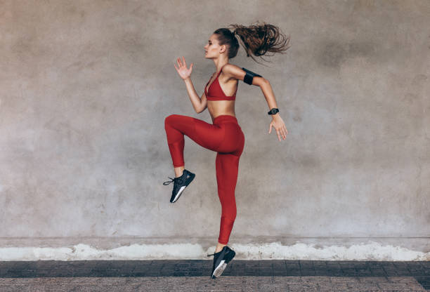 Sportswoman jumping and stretching Sportswoman jumping and stretching. Full length of healthy female exercising and jumping outdoors. cardiovascular exercise stock pictures, royalty-free photos & images