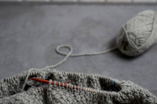 istock Gray unfinished sweater with a ball of threads on a gray background 963121500