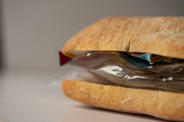 istock Fresh tasty panini sandwich with plastic waste and paper cardboard inside on white background. Recycled waste in our food concept 963121618