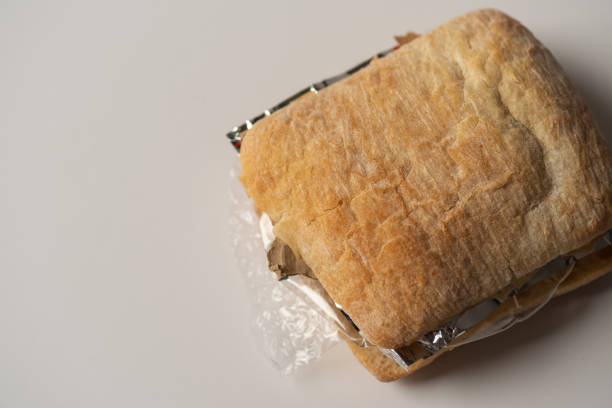 istock Fresh tasty panini sandwich with plastic waste and paper cardboard inside on white background. Recycled waste in our food concept 963121832