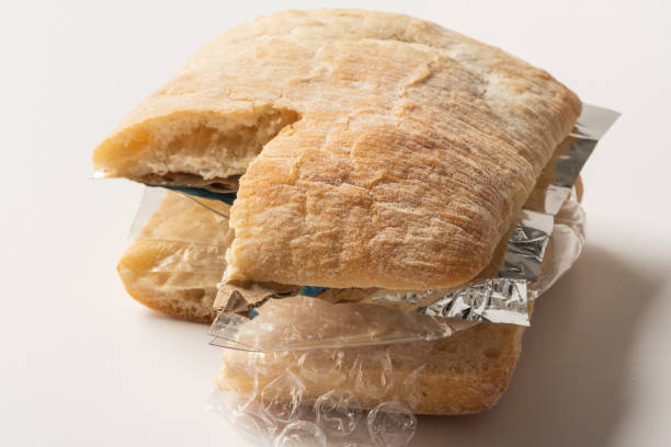 istock Fresh tasty cut out burger panini with plastic waste and paper cardboard inside on white background. Recycled waste in our food concept 963122594