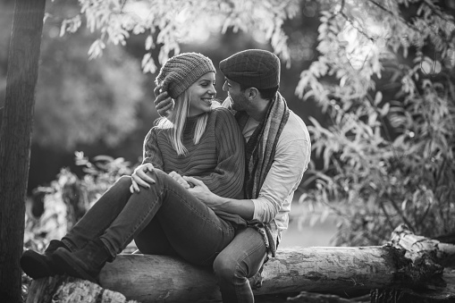 Young happy couple communicating while relaxing in nature. Black and white photography.