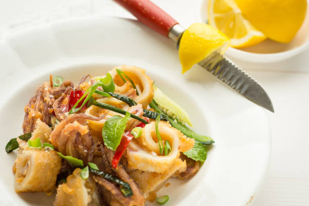 istock Fresh Fried Squids, Chili Pepper and Mint Leaves on White Plate 963125498