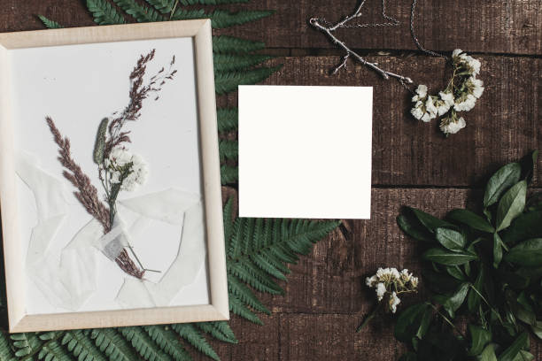 istock wedding invitation mock-up and rustic boutonniere under glass frame on wooden  background with fern leaves. rustic barn wedding concept. top view. flat lay, empty card 963126170