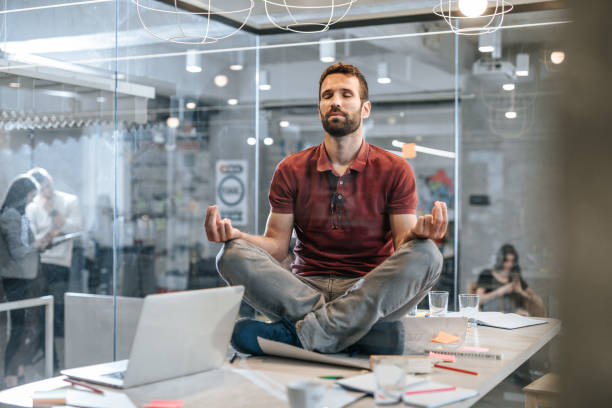若い男性起業家オフィスのテーブルの上のヨガを行使を緩和しました。 - zen like meditating yoga business ストックフォトと画像