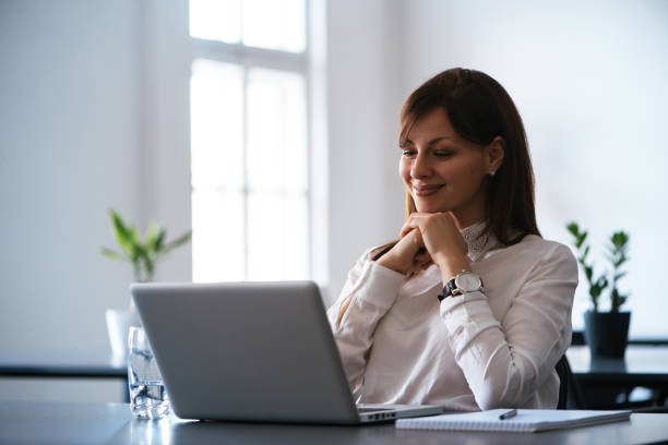 istock Attractive smiling young business woman using laptop at work desk 963131340