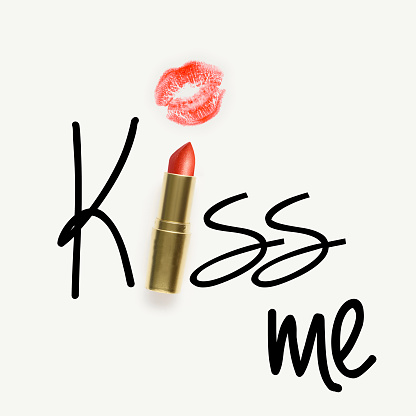 Creative concept photo of lipstick with sign kiss me on white background.