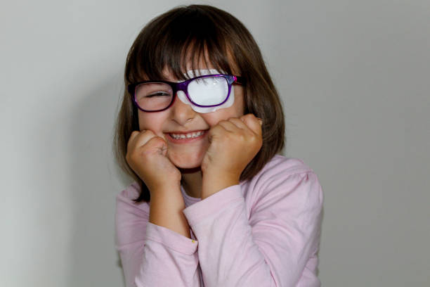 Little girl with eye patch Portrait of a little girl who is wearing an eyepatch to correct her vision, Girl with glasses and eyepatch one eyed stock pictures, royalty-free photos & images