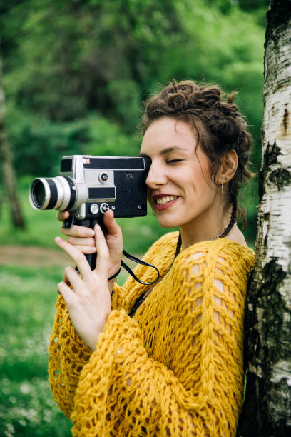 istock Young woman using an vintage cinema camera in a park 963137814