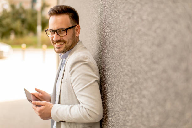 istock Young businessman with digital tablet by the grey wall 963142336