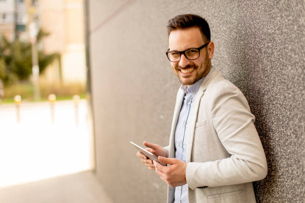 istock Young businessman with digital tablet by the grey wall 963142352