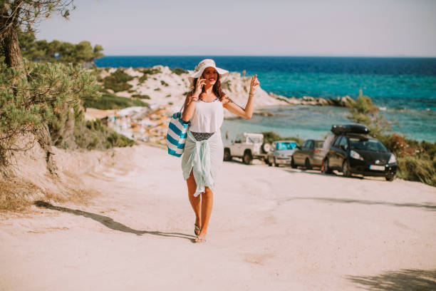 istock Pretty young woman with a bag using mobile phone on the beach 963143002