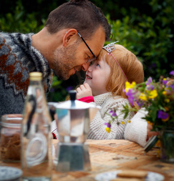 istock Father and daughter touching foreheads at table 963145438