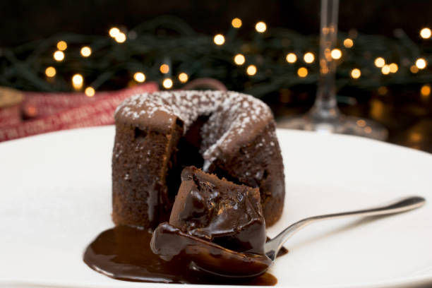 チョコレートの溶岩ケーキ プレート、クリスマス ライト、白地に粉砂糖で飾られて