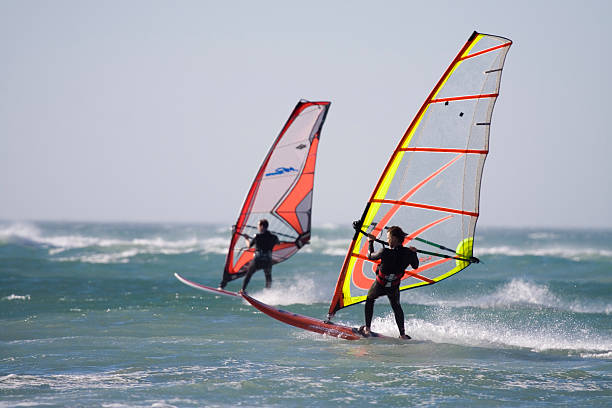 Two windsurfers on the water in wetsuits two windsurfer,blue sea,colourful sails windsurfing stock pictures, royalty-free photos & images