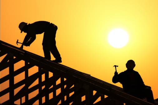 Mid-adult male Caucasian roofer, working on a roof beam at the construction site