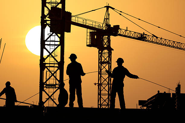 istock Silhouettes of men doing construction with a crane 96318824