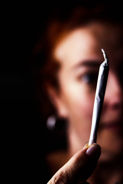 istock Close-up of marijuana joint held up in front of a persons face 963190162