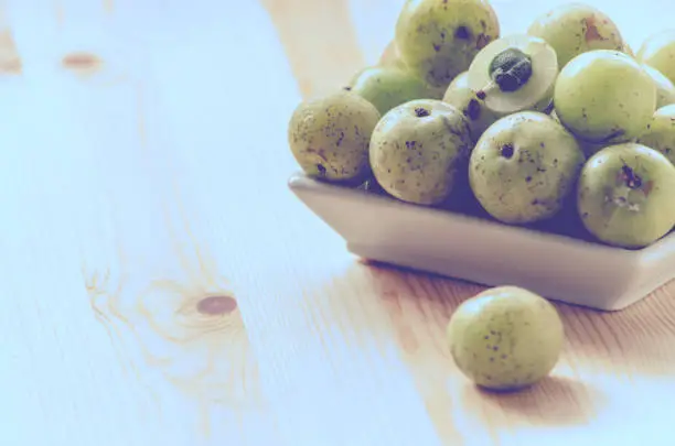 Indian Gooseberry: berry of high vitamin-c on the wooden background: vintage tone
