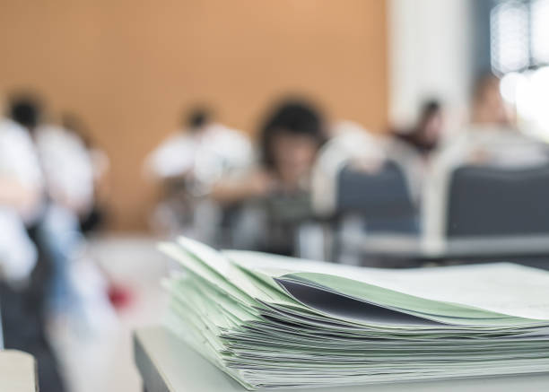 istock Exam answer sheet or application paper blurry view on table in examination room with blur education background of school university students taking exam test writing answer in seat row with stress 963194528